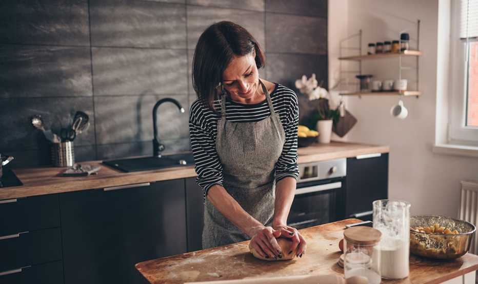 Mujer amasando la mezcla para un postre en la mesa de su cocina