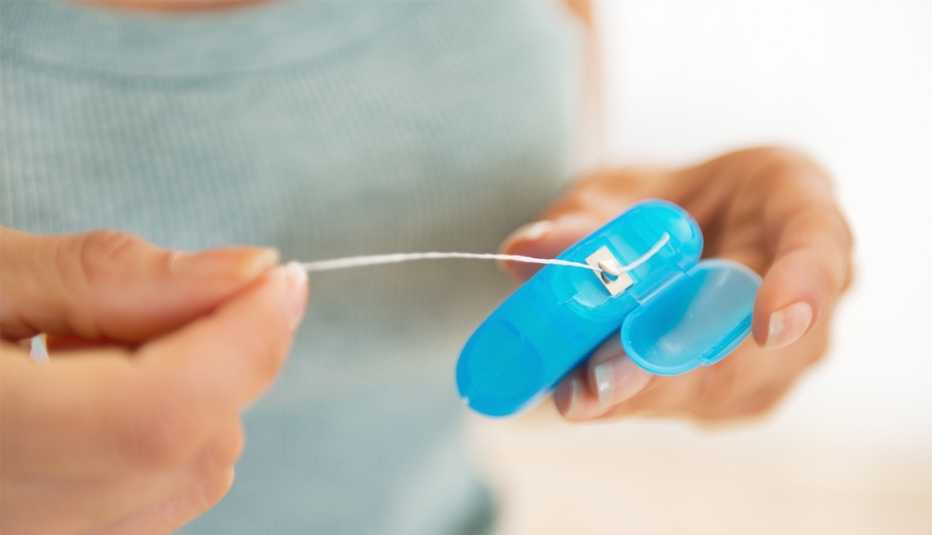 Primer plano de una persona cortando un hilo dental Primer plano de una persona cortando un hilo dental