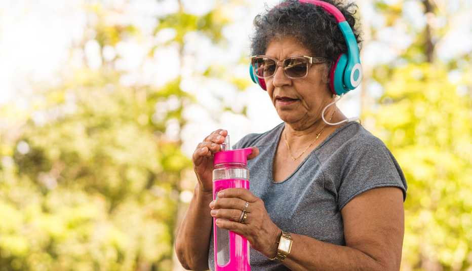 Una mujer toma agua mientras se ejercita al aire libre