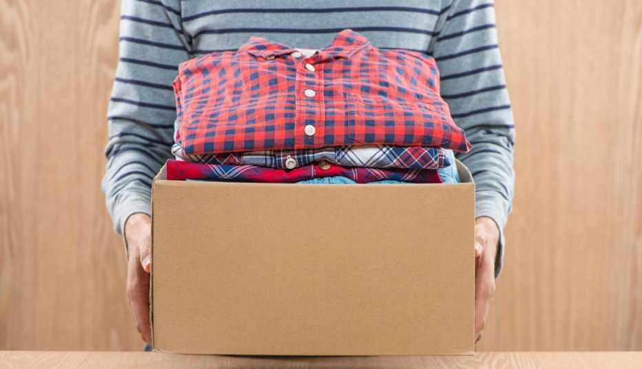 Persona lleva una caja llena de ropa