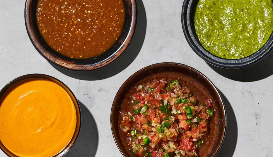 en el sentido de las agujas del reloj, desde arriba a la derecha, salsa verde, pico de gallo, salsa de chile de árbol y salsa roja
