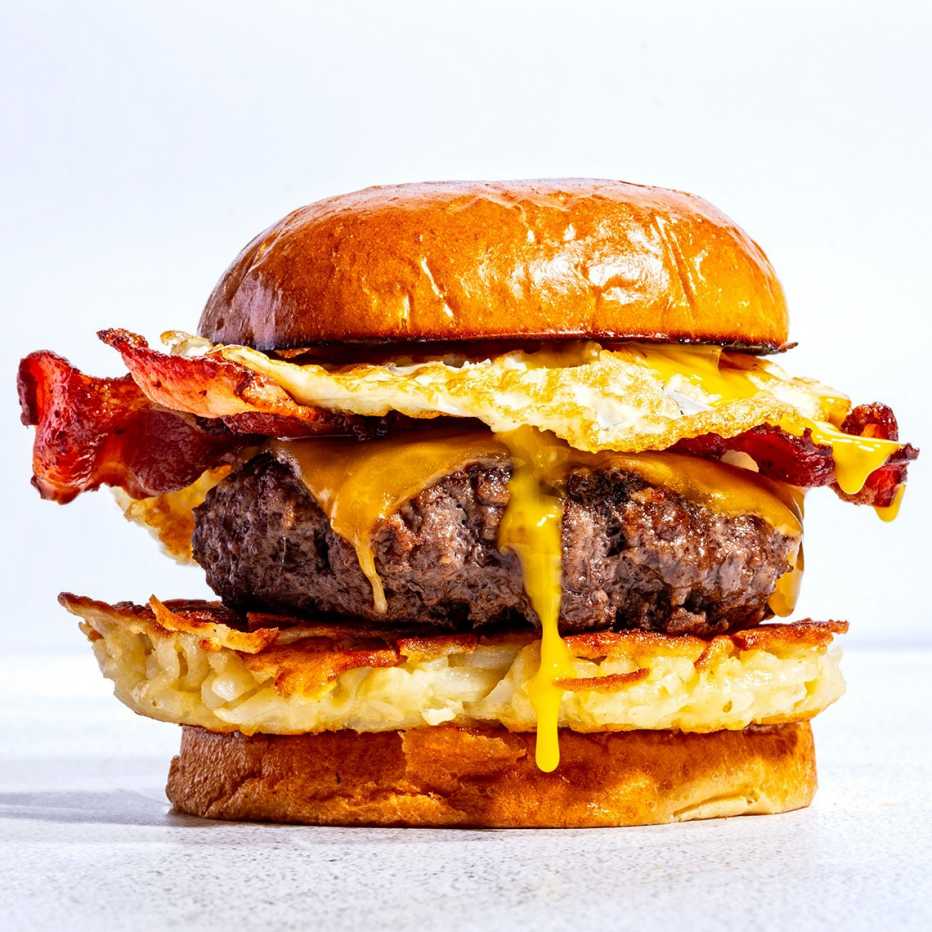 Una hamburguesa de desayuno con papas, una hamburguesa con queso, tocino y huevo.