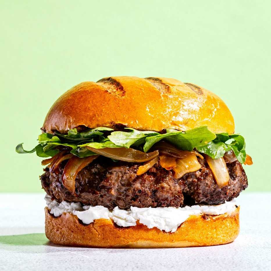 Una hamburguesa con queso de cabra, cebollas caramelizadas y verduras.