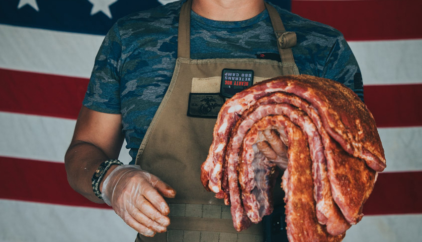 someone holds a rack of ribs in front of an american flag