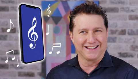 Un hombre mirando un teléfono móvil con notas musicales flotando.