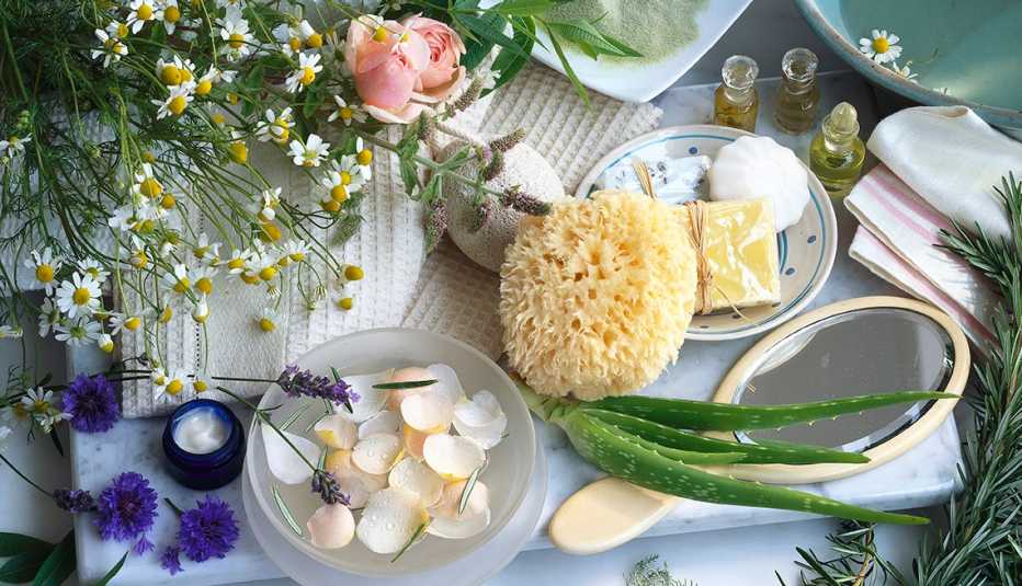 Mesa con flores y plantas, aloe vera, aceites aromáticos, esponja natural y jabones Mesa con flores y plantas, aloe vera, aceites aromáticos, esponja natural y jabones