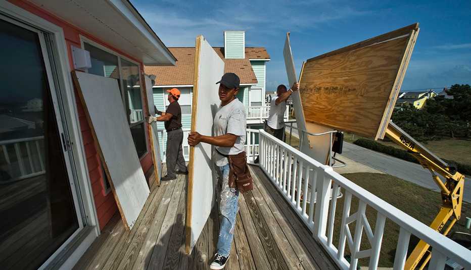 Hombres poniendo planchas de plywood en una casa junto a la playa.
