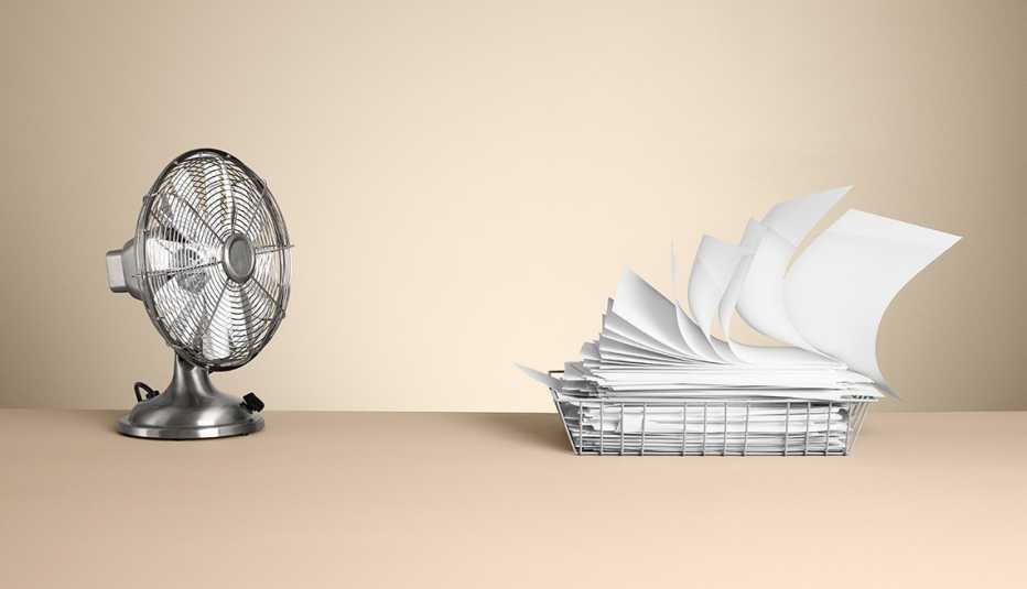 Ventilador echando aire hacia unos papeles.