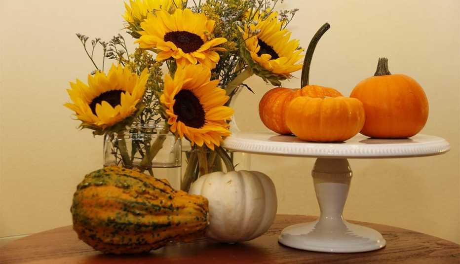 Centros de mesa de distintas alturas Calabazas puestas sobre una base alta de porcelana rodeada de flores