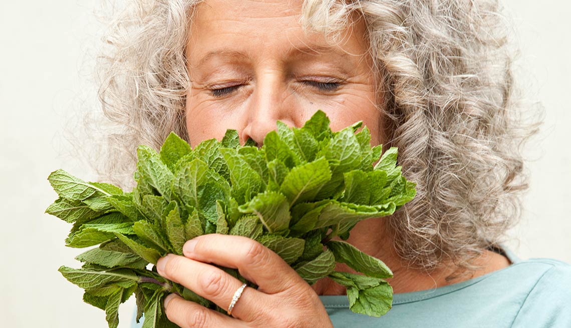 Una mujer oliendo un manojo de menta