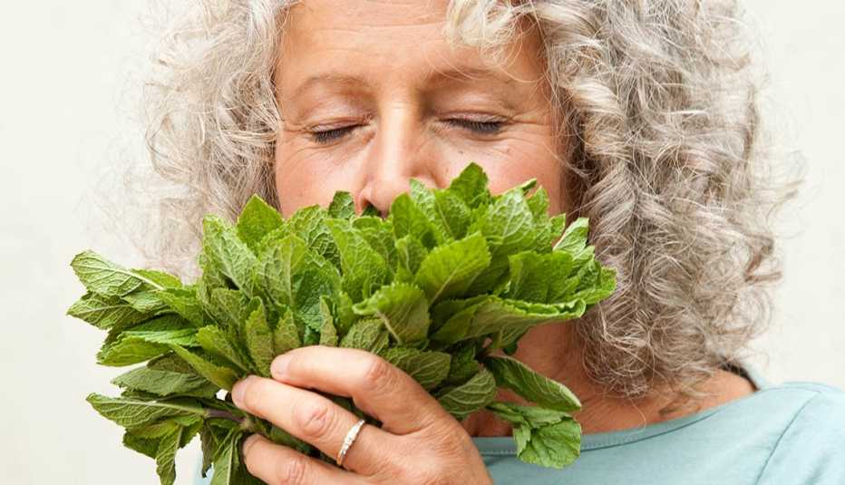Una mujer oliendo un manojo de menta