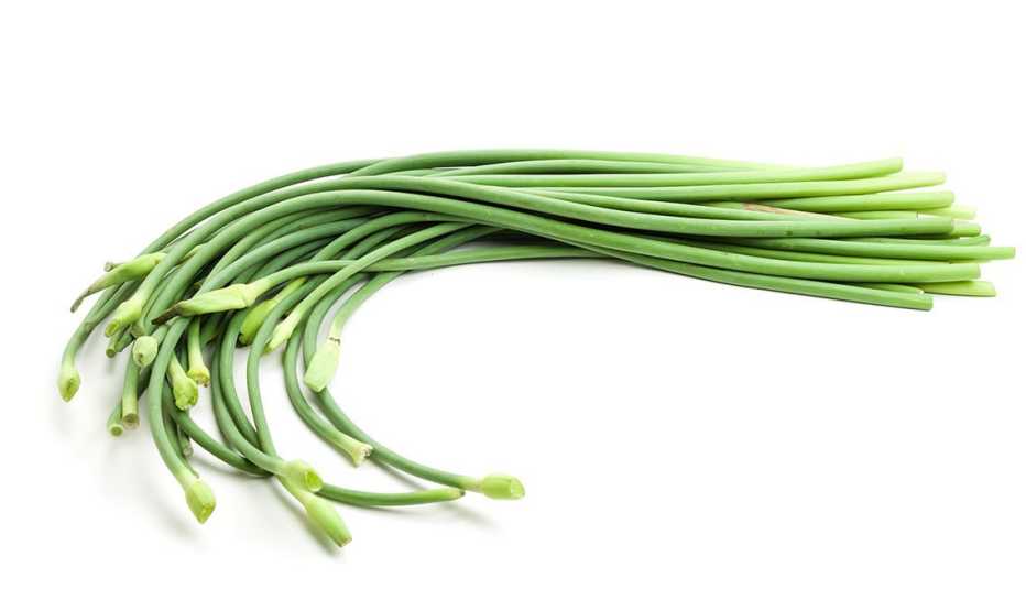 Varias plantas de ajo sobre una superficie blanca