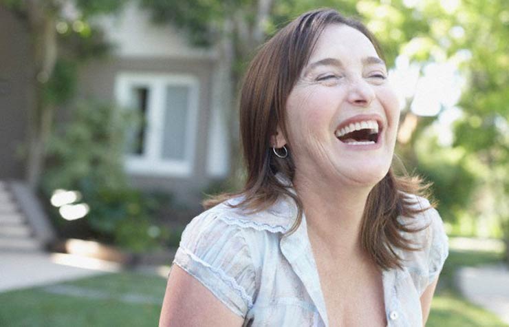 Mujer de pie al aire libre riendo, Espiritualidad: 5 claves para ayudarle a dejar de lado la negatividad Mujer de pie al aire libre riendo, Espiritualidad: 5 claves para ayudarle a dejar de lado la negatividad