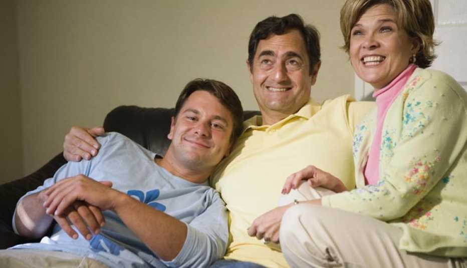 Familia sentada en un sofá y sonriendo - ayudar a las familias a apoyar a un miembro de la familia con discapacidad Familia sentada en un sofá y sonriendo - ayudar a las familias a apoyar a un miembro de la familia con discapacidad