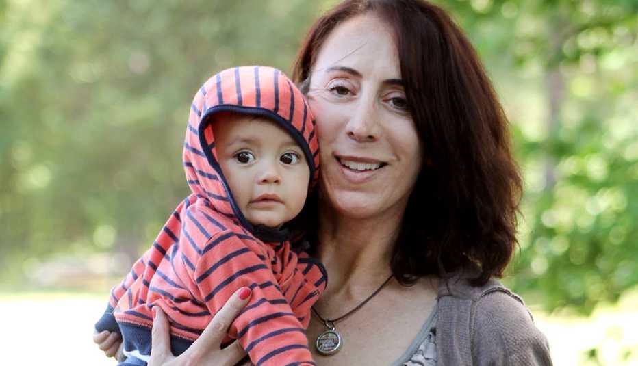 Mujer adulta sostiene a su bebé adoptado.