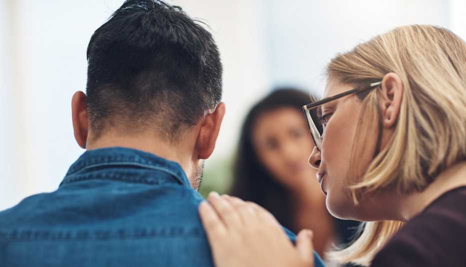 Una mujer pone su mano sobre el hombro de un hombre Una mujer pone su mano sobre el hombro de un hombre