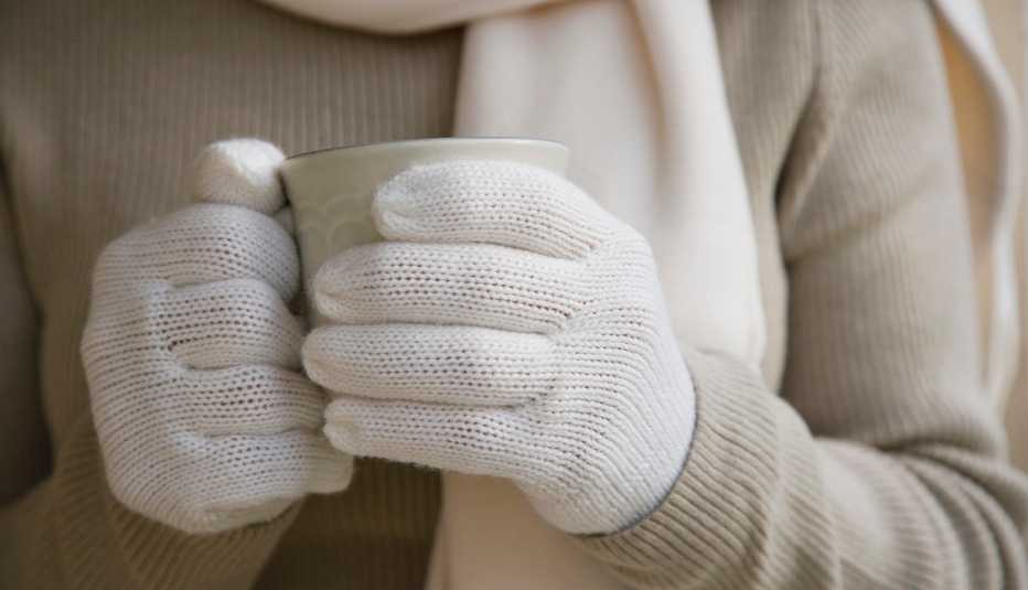 Mujer sosteniendo una taza con guantes, bufanda y abrigo Mujer sosteniendo una taza con guantes, bufanda y abrigo