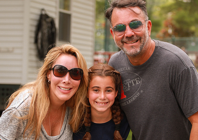 Valerie Zucker sonríe junto a una niña y un hombre