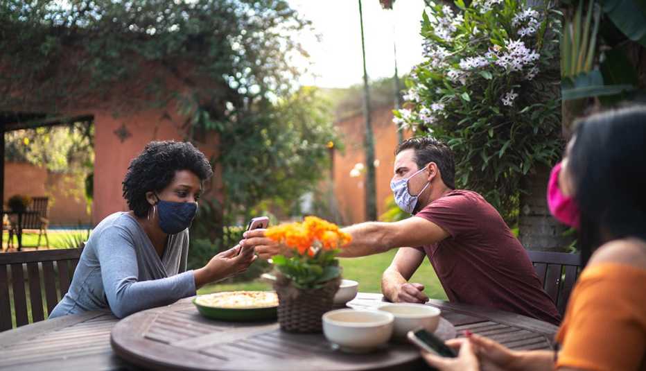 Varios amigos comparten en el patio de una casa, todos usan mascarillas