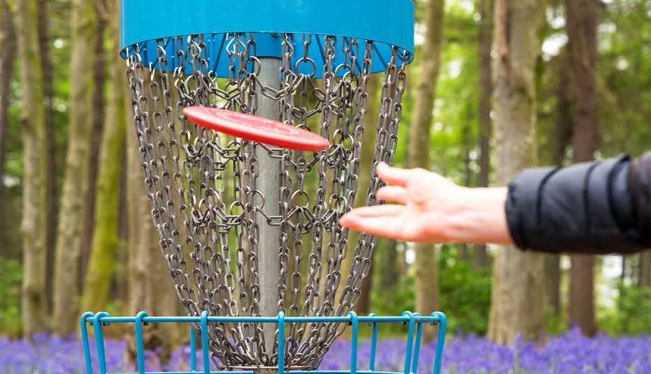 Un jugador lanza un disco rojo a corta distancia hacia la canasta Un jugador lanza un disco rojo a corta distancia hacia la canasta