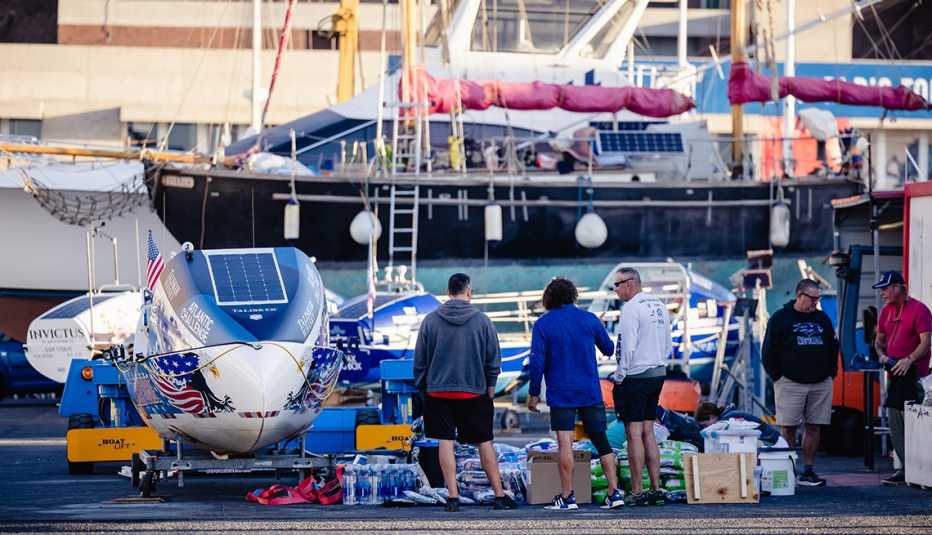 Miembros del equipo de remo Foar From Home, compuesto por veteranos, posan en el muelle junto a su bote