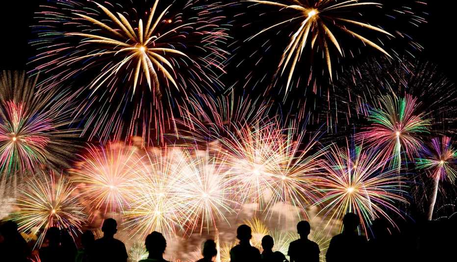 Personas observan fuegos artificiales en la noche