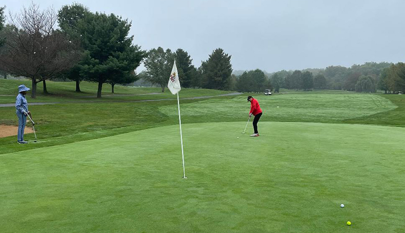 Un golfista golpea la pelota de golf muy cerca del green