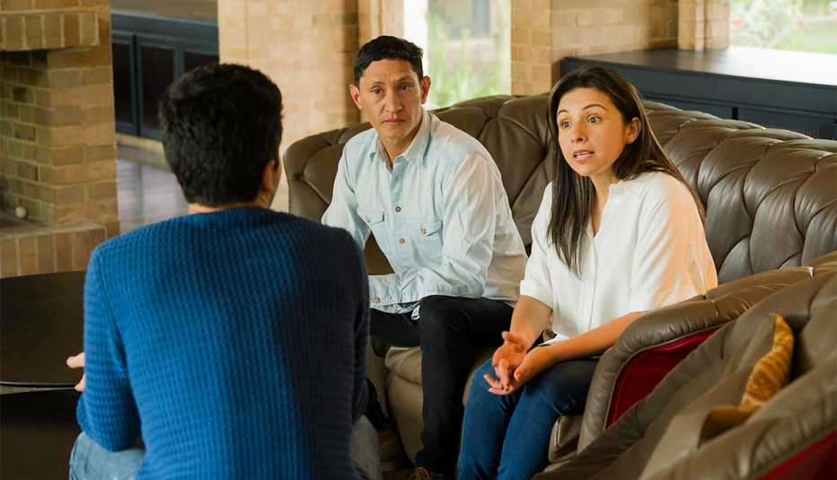 Padres hablan con su hijo en la sala de su casa