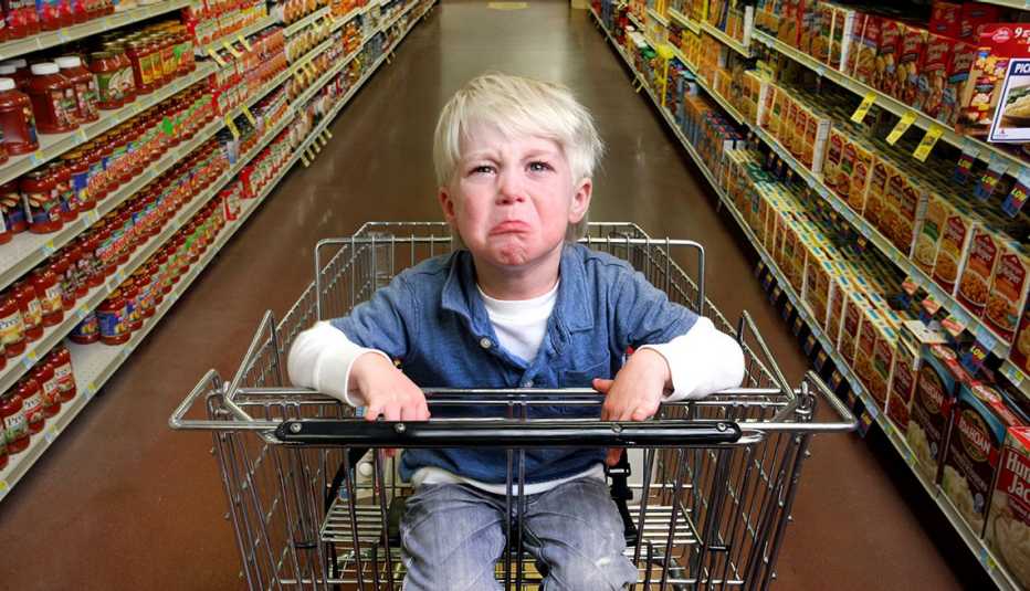un niño con una rabieta en un carrito de compras un niño con una rabieta en un carrito de compras