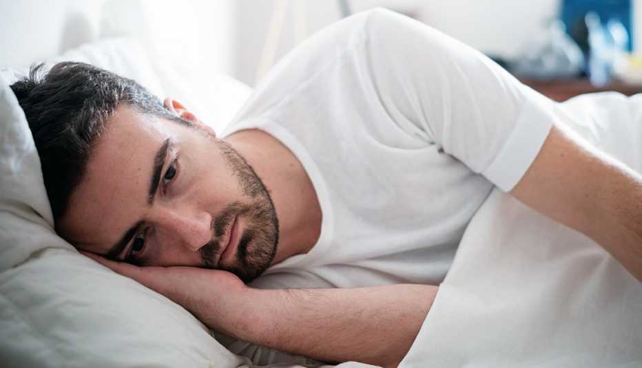 Hombre acostado sin poder dormir