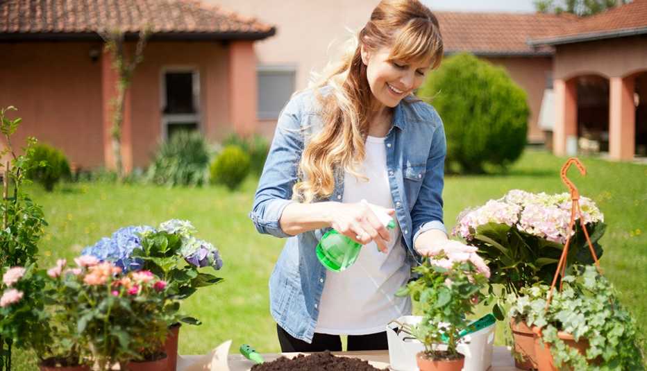 Una mujer en su jardín regando sus plantas