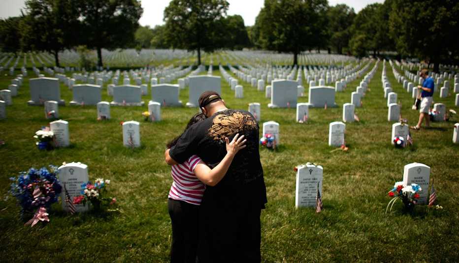 Personas honrando a un ser querido en un cementerio