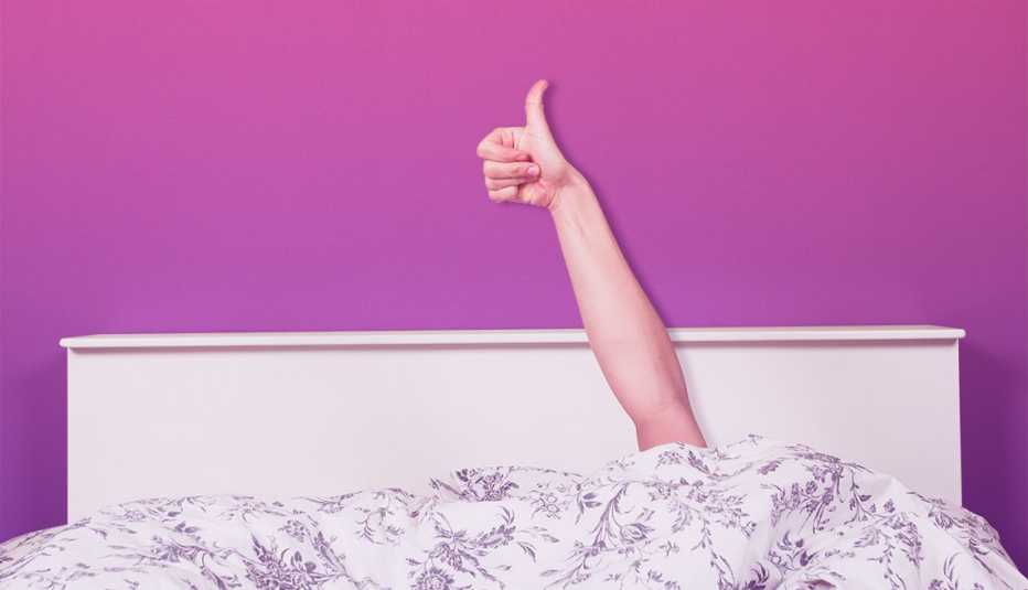 Una persona acostada en su cama y muestra su pulgar arriba