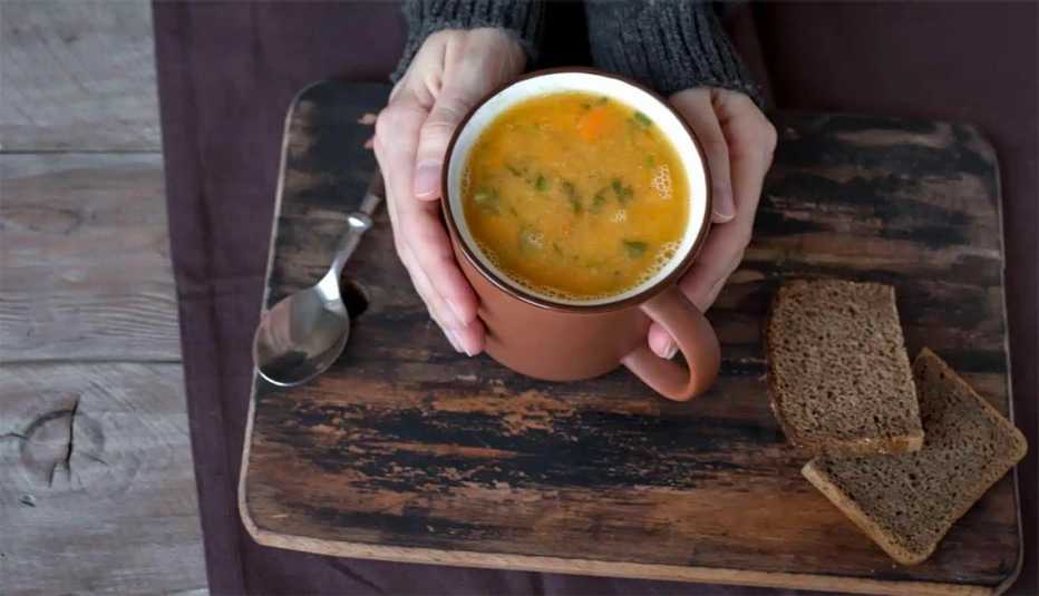 a person holding cup of hot Lemon Coriander soup
