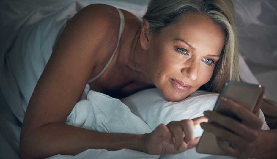 Mujer viendo el teléfono móvil en la cama