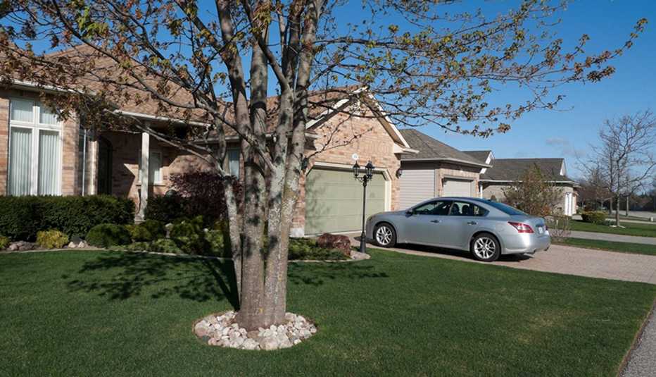 Casa con un auto gris parqueado frente a su casa