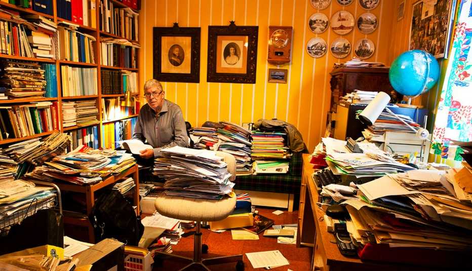 Un hombre sentado en un estudio desordenado.