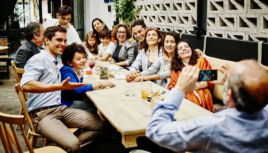Hombre se inclina hacia atrás para tomar una foto de un grupo familiar en un restaurante