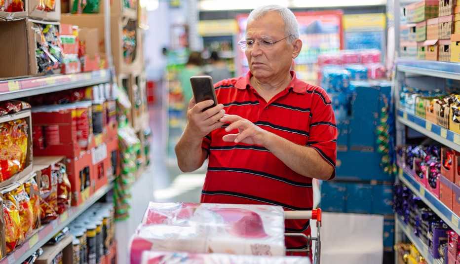 Hombre revisando la lista de compras en su teléfono inteligente Hombre revisando la lista de compras en su teléfono inteligente