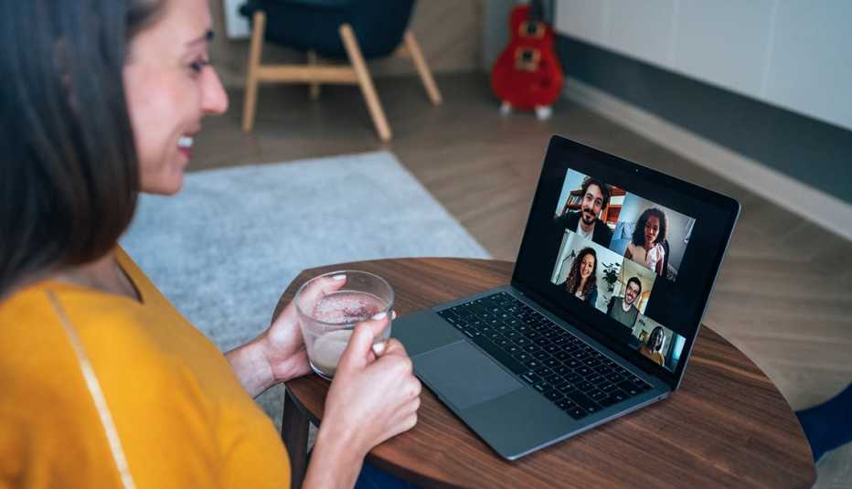 Mujer que usa una computadora portátil para una videoconferencia con varias personas Mujer que usa una computadora portátil para una videoconferencia con varias personas