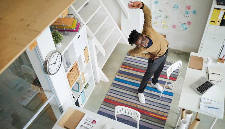 Hombre haciendo estiramientos en la oficina de su casa