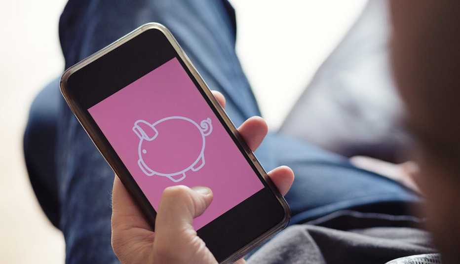 Hombre sostiene un teléfono inteligente con la imagen de un cochino en la pantalla Hombre sostiene un teléfono inteligente con la imagen de un cochino en la pantalla