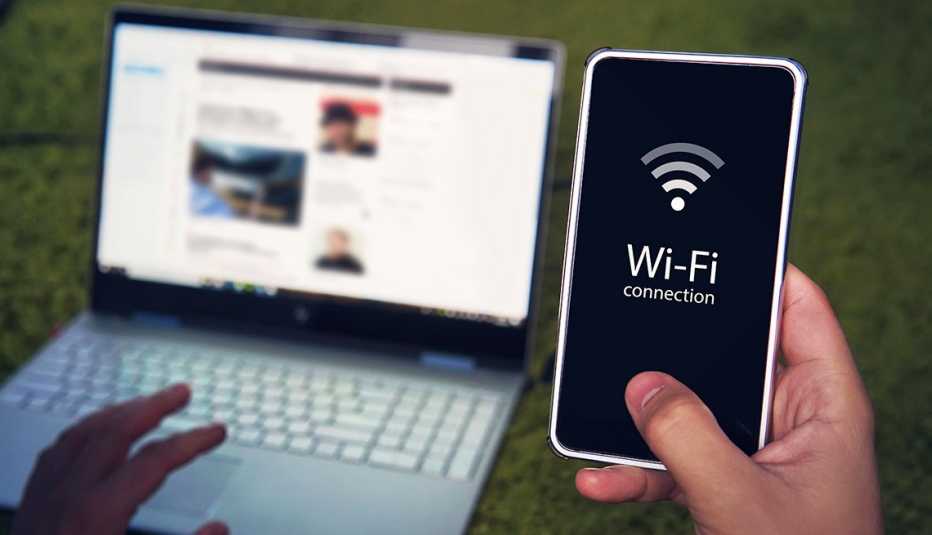 Una persona trata de conectar su computadora a la red wifi de su teléfono