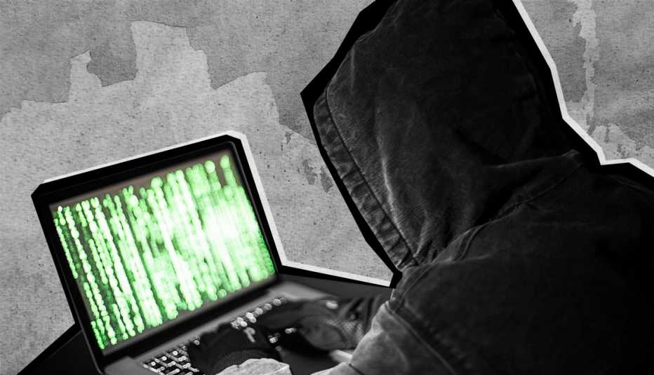 Un hacker con capucha escribiendo en una computadora Un hacker con capucha escribiendo en una computadora