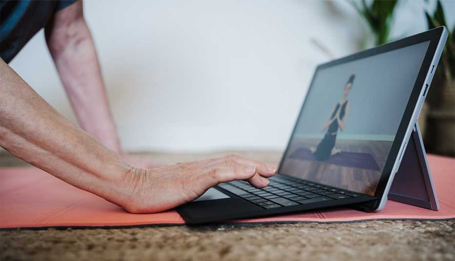 Persona usa una tableta para ver un video tutorial de yoga Persona usa una tableta para ver un video tutorial de yoga
