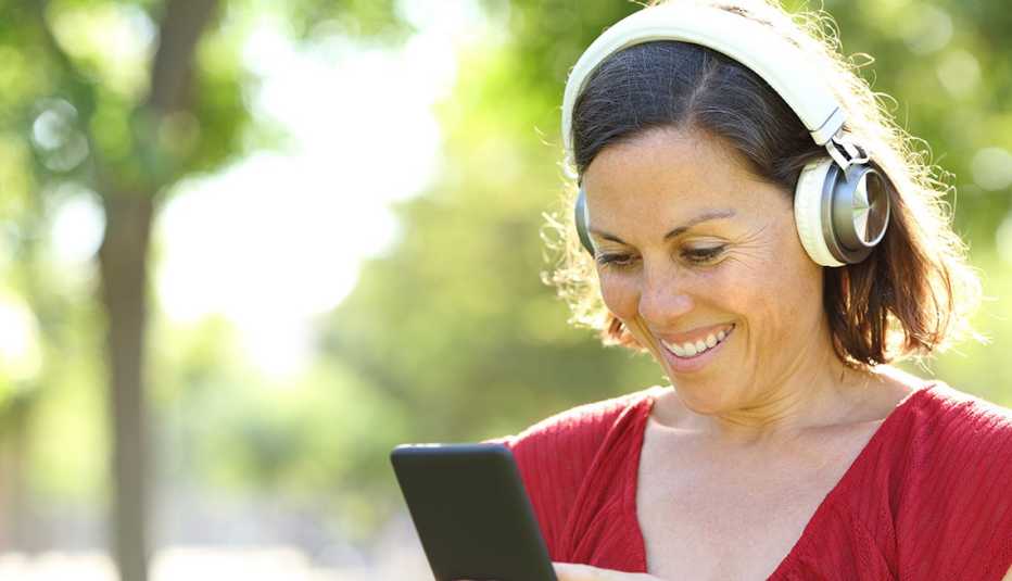 Una mujer con una camisa roja sonríe mientras usa auriculares 