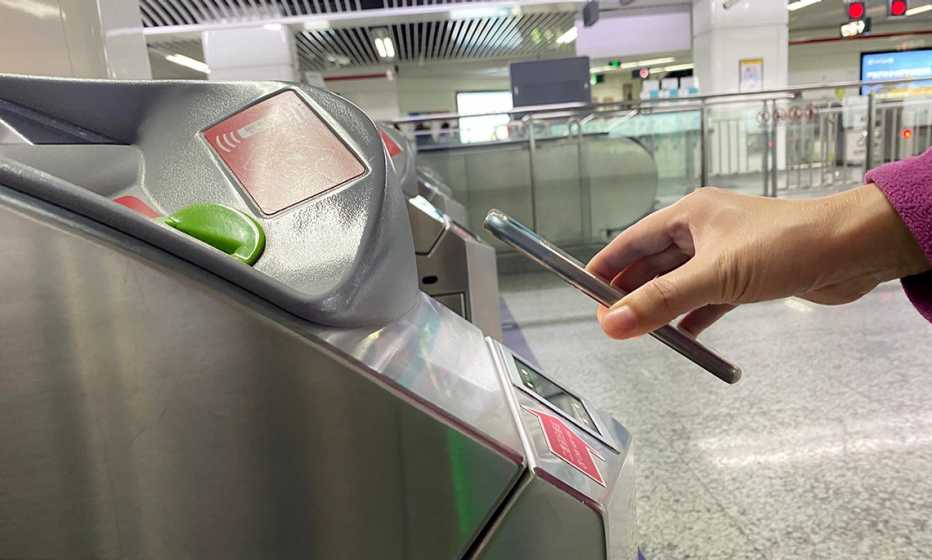  Una mujer usa un teléfono inteligente para ingresar a una estación de tren.