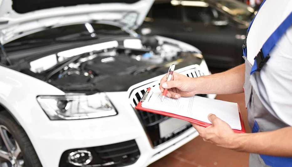 Mecánico de automóviles sosteniendo un portapapeles en un garaje.