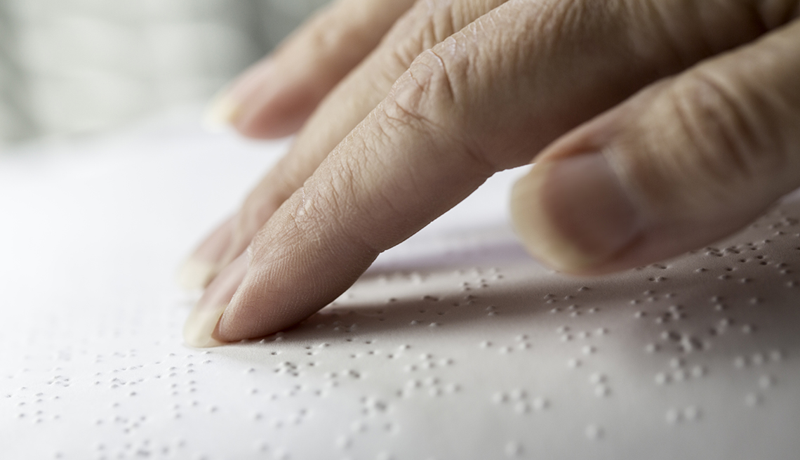 persons hand reading braille book