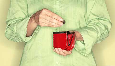 Una mujer con camisa verde pone una moneda en una billetera roja que sostiene